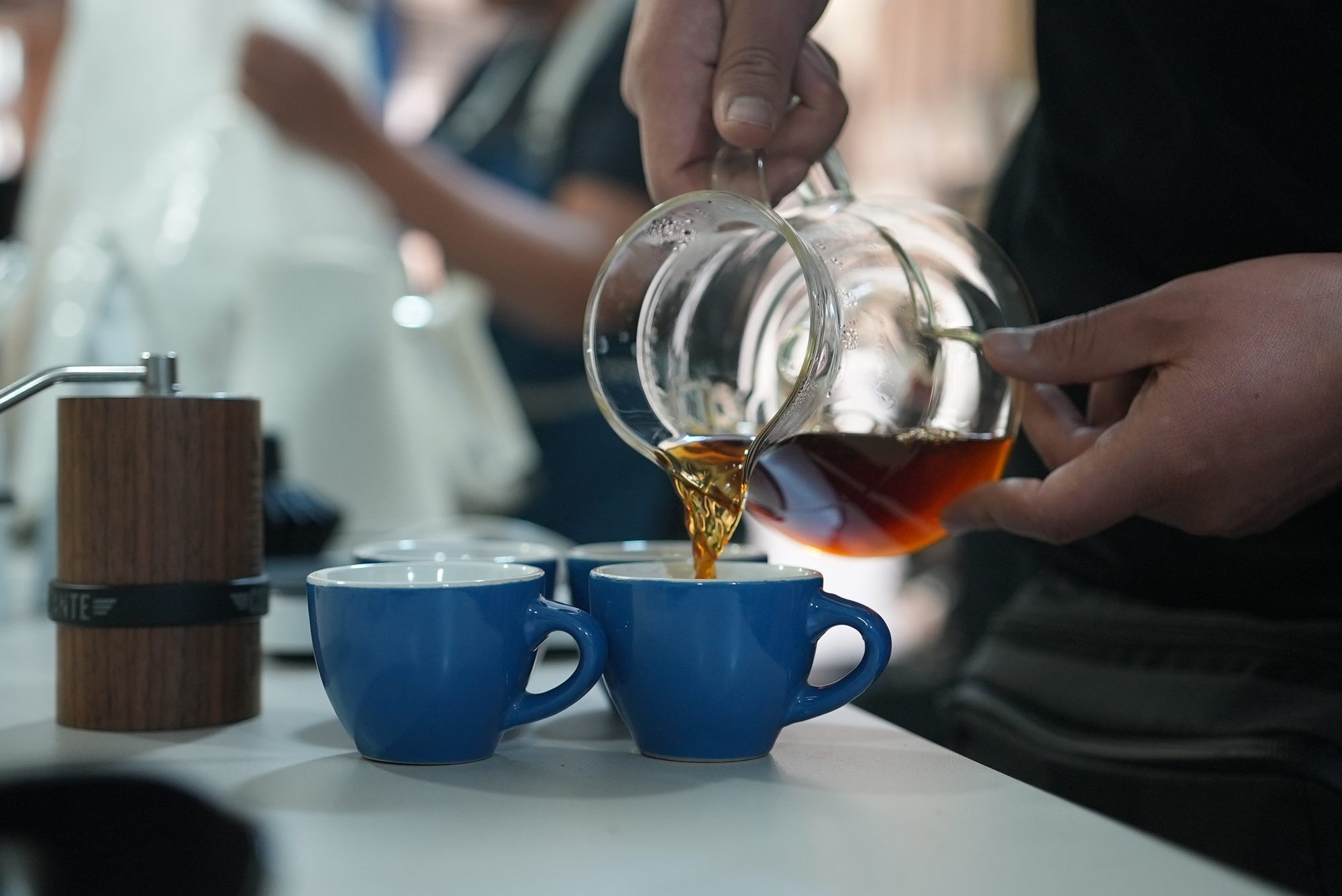 Barista pouring V60 pour-over coffee into blue cups at the Cusco coffee lab
