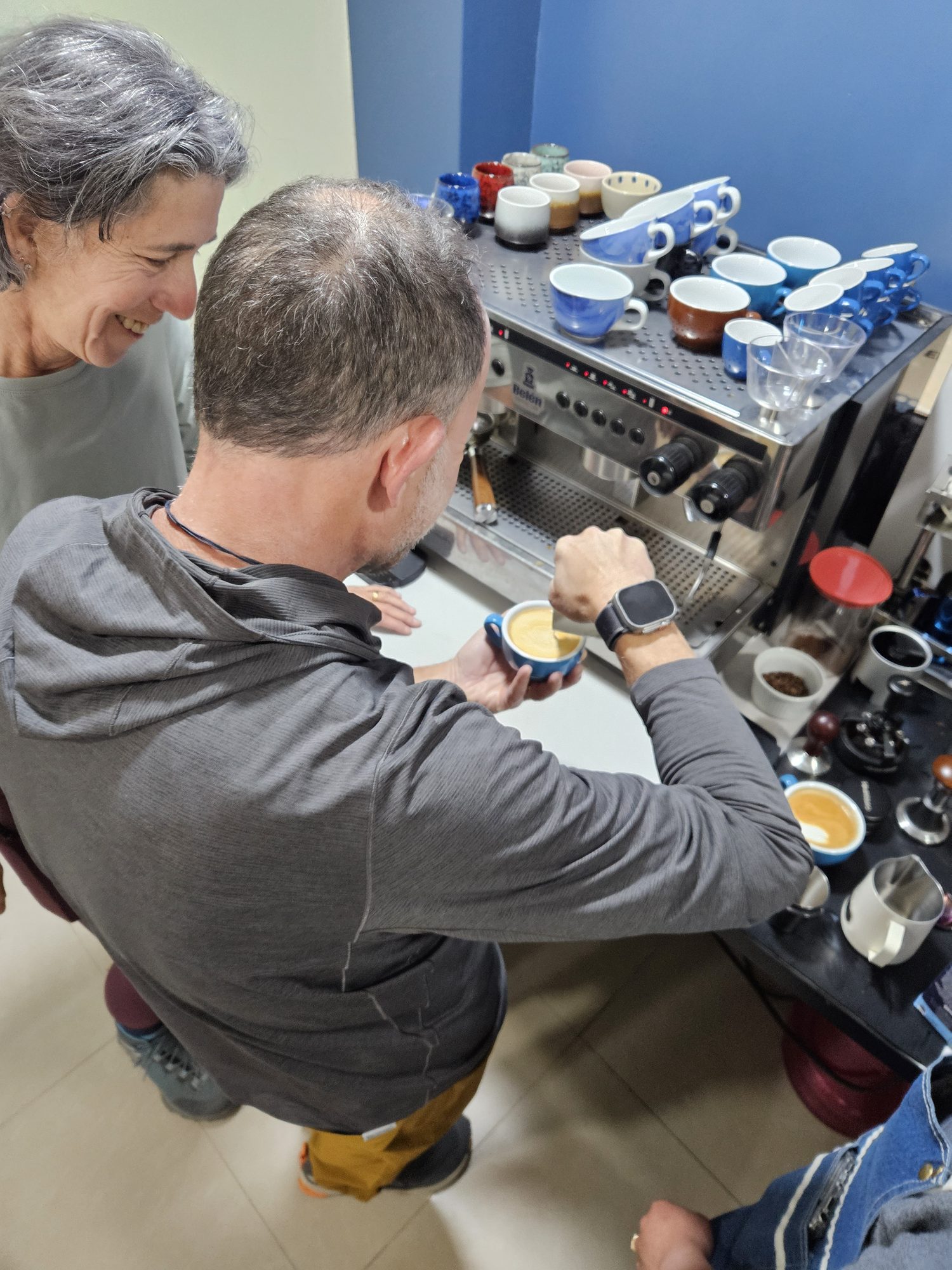 Barista pulling an espresso shot beside a steaming pitcher at the Cusco coffee lab